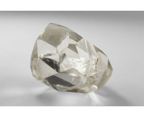 A large, freeform facetted quartz with with approximately 21 facets, and with internal structures producing 'rainbow' reflect