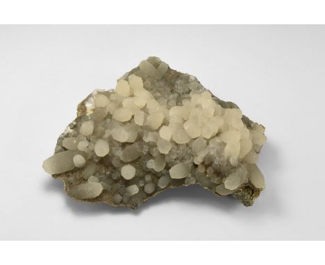 A sheet of calcite crystals on a rock groundmass from Maharachita, India, with unusual step growth barrel forms. Found Mahara