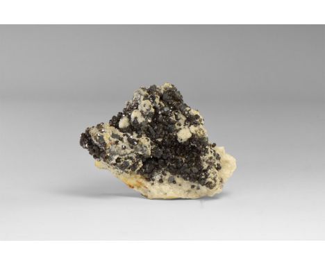 A fine specimen of boulangerite with well-formed crystals and accessory calcite, on matrix, with an old adhesive tape label t