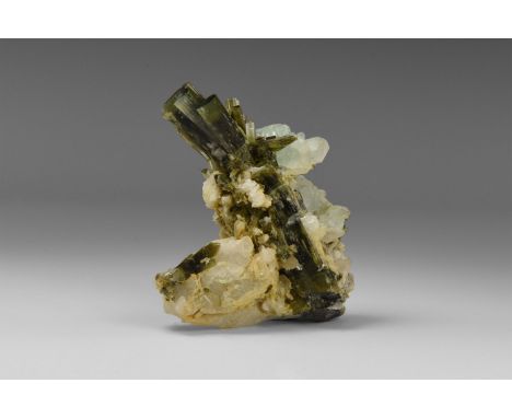 A group of fine green tourmaline crystals on albite, with overgrowths of fluorite, from Pakistan; in old white card tray with