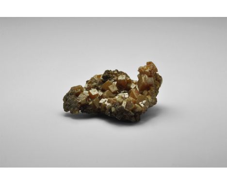 A group of blocky orange vanadinite crystals on a groundmass of an unidentified mineral, from Mexico, in old white card tray.