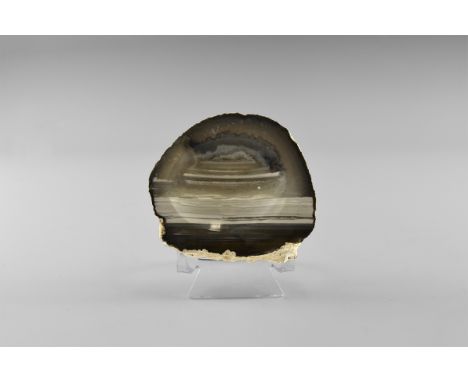 A shallow bowl or dish carved from white, blue-grey, and black banded agate, from Brazil, with complex interweaving banding o