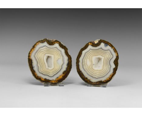 A sawn and polished pair of banded white agate geodes with brown agate rim and centre hollow lined with quartz crystals, with
