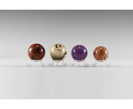 A group of four select grade gemstone spheres including amethyst, slightly smoky rock crystal, brecciated jasper, and banded 