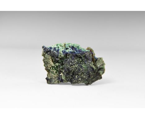 A crust of blocky azurite crystals dotted with spherical aggregates of malachite, in old white card tray, with adhesive tape 