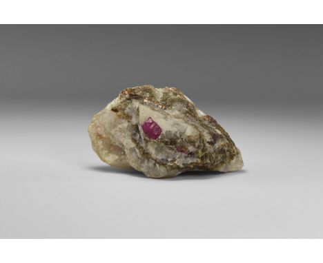 A rich red gemmy, finely formed ruby crystal in a marble matrix, with accessory biotite, from Afghanistan; in old white card 