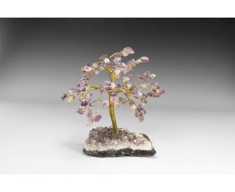 A large size gemstone tree consisting of a brass trunk and branches tipped with polished amethysts, mounted on a section of a