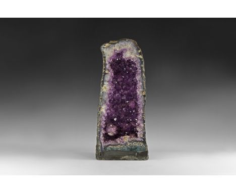 A sawn half of an amethyst geode with fine amethyst crystals, including one amethyst 'porcupine', the polished section showin