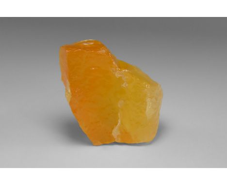 A piece of translucent Mexican calcite with an unusually vibrant orange colour, in old white card tray with label reading: 'O