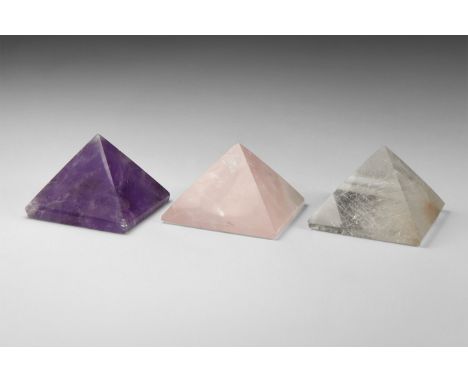 A group of three finely cut gemstone pyramids including one each of rutilated quartz, amethyst, and rose quartz. From the his
