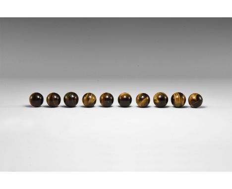 A group of ten gold tiger-eye spheres the size of marbles, all showing bright colour banding. From the historic ‘Victorian Mu