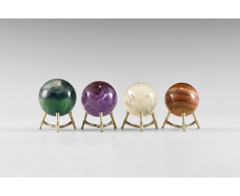 A group of four select grade gemstone spheres comprising one each of amethyst, rock crystal with internal 'rainbows', purple 