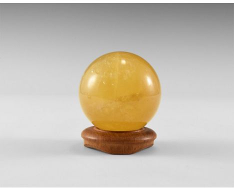 A polished sphere of yellow-brown 'citrine' calcite with reflective internal features, and with antique turned wood stand. Fr