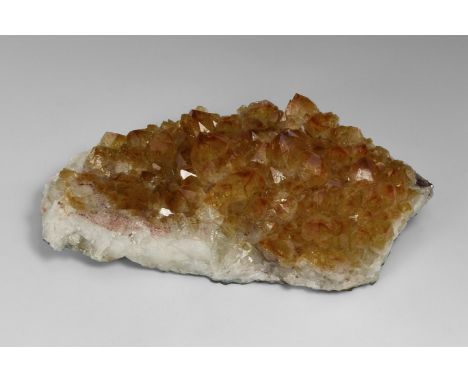 A sheet of yellow-brown citrine crystals from Brazil, on a white quartz base, some crystal tips a darker red-brown. From the 