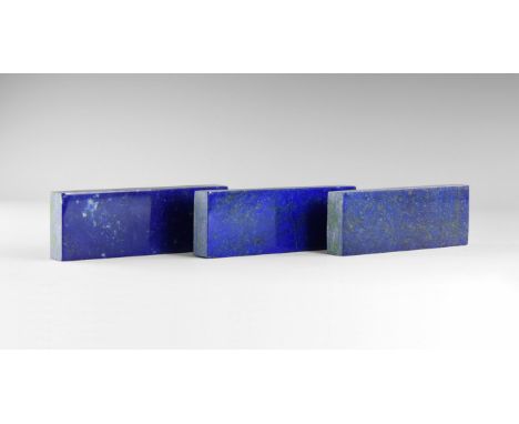 A group of three gem-quality lapis lazuli plaques, each 15mm thick, suitable for re-cutting into gemstones, in old white card