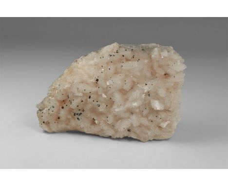 A crust of finely-formed pink dolomite crystals on a groundmass of dolomitic limestone, with small crystals of an unidentifie