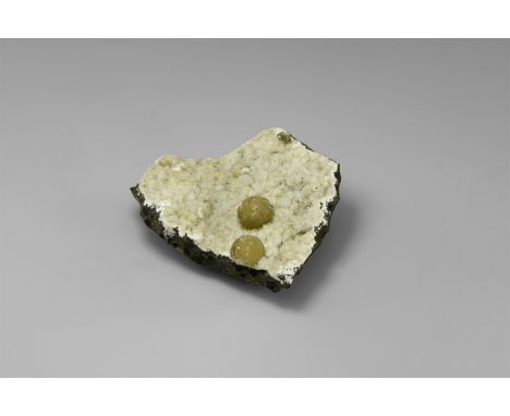 A pair of spherical aggregates of the zeolite thomsonite on quartz, from Maharashita, India. Found Maharashita, India; from t