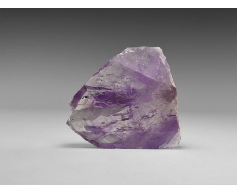 A sawn and polished section of a large, parallel-growth amethyst crystal with intergrowth lines visible, mostly transparent, 