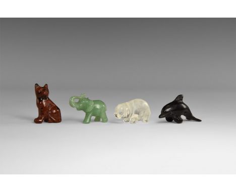 A group of four finely carved gemstone animals including a cat in red-brown obsidian, a dolphin in black onyx, a pig in rock 