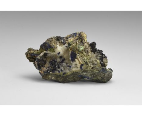 A matrix specimen of azurite crystals, some transparent, with accessory calcite, with detached adhesive tape label reading: '