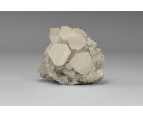 A fine group of barrel-shaped calcite crystals with triangular terminations, on matrix; in old white card tray. From the hist