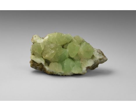 A matrix specimen of green prehnite consisting of several rounded aggregates on a rock groundmass, from India, in old white c