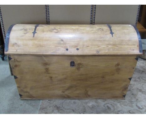 A large pale pine domed top trunk, with banded hinges over a locking cover (with key) flanked by carrying handles, 73 cm high