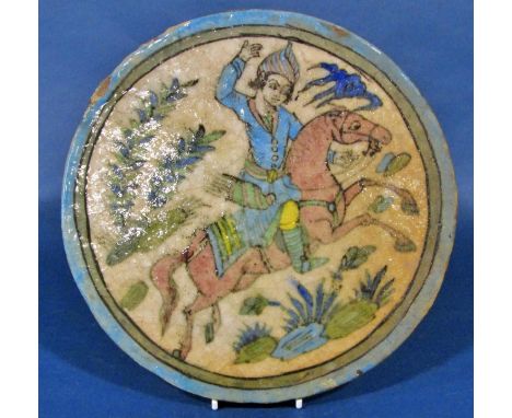 A large circular Iznik type earthenware tile, decorated with horse and rider, impressed decoration of deer and foliage verso,