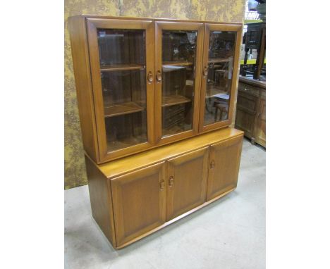 An Ercol ‘Golden Dawn’ elm sideboard / cabinet, the lower section enclosed by three panelled doors, the upper section fitted 