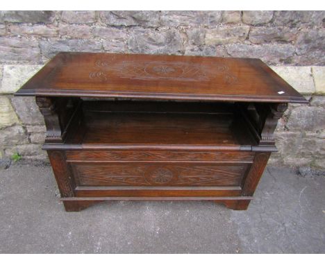 An Edwardian oak monks bench, with shallow carved detail and arms in the form of lions. 