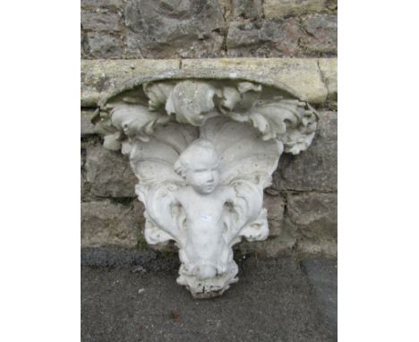 A weathered composition stone console bracket, in the rococo style, moulded with putti, within scrolling acanthus mounts belo