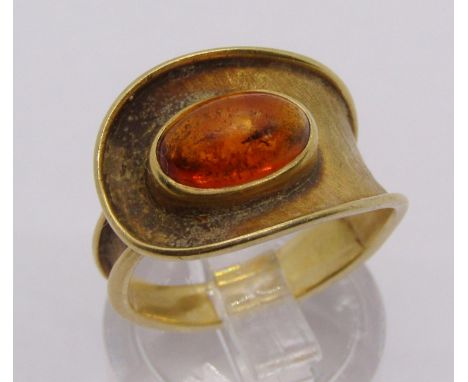 Stylised yellow metal ring set with a cabochon hessonite garnet, stamps worn, size M, 4.6g 