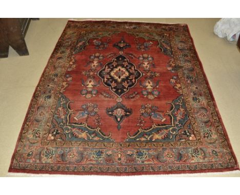 A Hamadan carpet woven in shades of red and blue, the border with stylised flowers, diamond shaped medallion to centre. 212cm