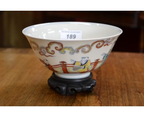 A Chinese flared cylindrical bowl, painted in polychrome with figures by a fence, cloud scroll board, 15.5cm diam, six charac