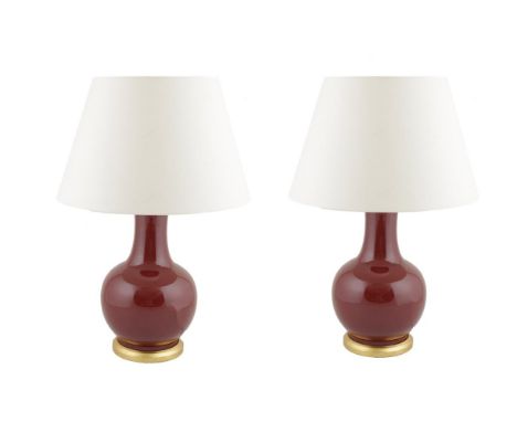 A PAIR OF SANG DE BOEUF CERAMIC VASE SHAPED TABLE LAMPS, of circular baluster form, raised on gilded circular bases, with pla