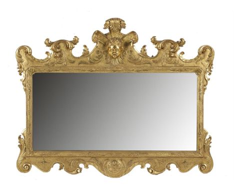 A GEORGIAN STYLE GILTWOOD AND GESSO SHAPED RECTANGULAR OVERMANTLE MIRROR, surmounted with a scrollwork frieze centred with a 