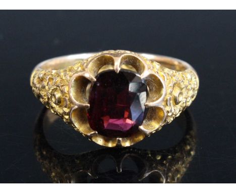An Edwardian 9ct gold and garnet set dress ring, the oval cut claw set garnet in a tapering setting with leaf and flower carv