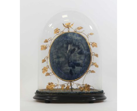 A Victorian glass dome, upon an ebonised wooden plinth, height 44cm, containing a brass and velvet clad mount, the frame in t
