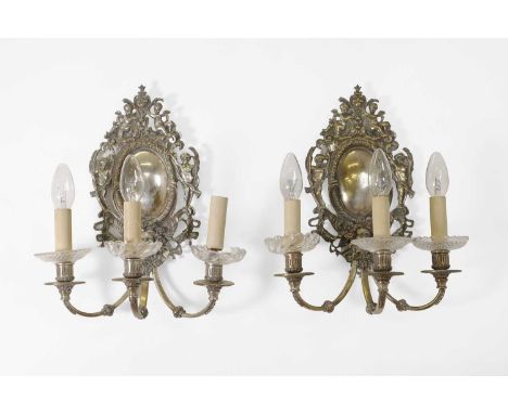 A pair of silvered-brass wall lights, in the Italian 18th-century style, each backplate in the form of an oval medallion with