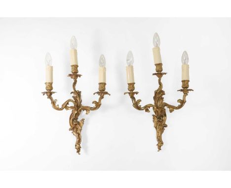 A pair of Louis XV-style gilt-metal wall lights, late 19th/early 20th century, French, each in the rococo style, issuing thre