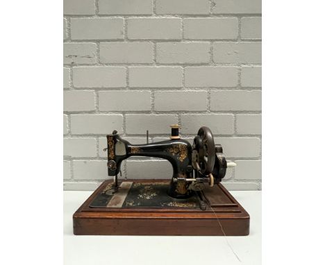VIntage cast iron sewing machine with a wooden base. Black with golden decals. Height: 31 cm. Width: 46 cm. Depth: 24 cm. Con