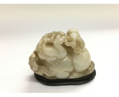 A carved jade figural group of two mythical creatures raised on a hardwood stand, approx length 9cm. NO RESERVE