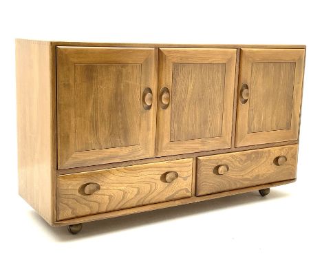 Ercol sideboard, fitted with three cupboards enclosing shelving above two long drawers to the base, raised on castors Dimensi