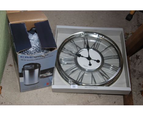 A clock and a stainless steel tea/coffee pot.