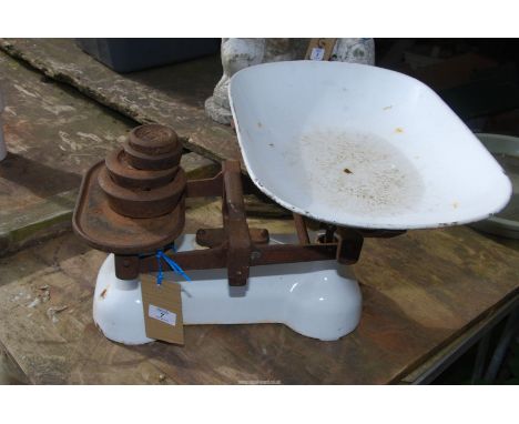 A set of enamel shop scales with weights.