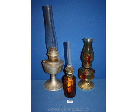 Three oil lamps including one with coloured glass, glass trunk design and a super Aladdin.