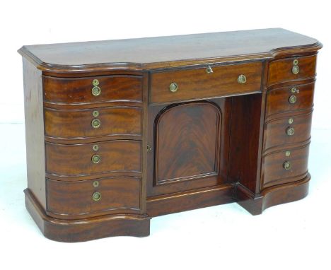 A Victorian mahogany knee hole desk, of serpentine, breakfront outline, with six drawers and two cupboards, with brass ring h