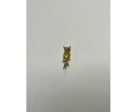 A 9ct gold owl brooch, perched on a branch, the feathers bright cut and engraved, set with a pair of ruby eyes, 4cm, marked 3