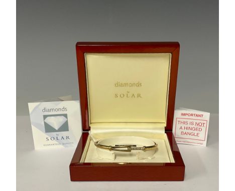 A 9ct gold bangle, set with a band of illusion set diamond chips, marked 375, 6cm interior, 6.4g, boxed 