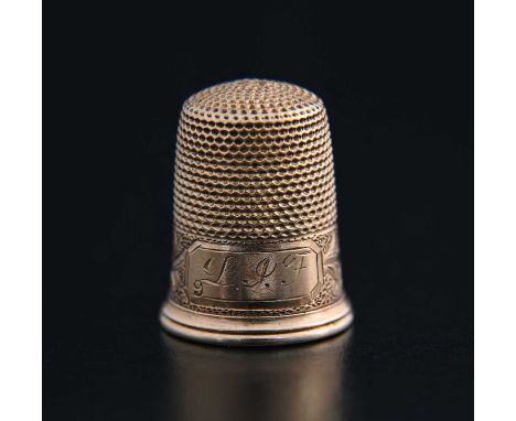 A twentieth-century gold thimble, decorated with a band of foliate scrolls, initialled 'LPF' or similar, the interior marked 